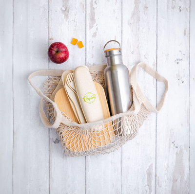Bamboo sustainable cutlery with iron flask in a lace bag with apple and vegan gummy vitamins