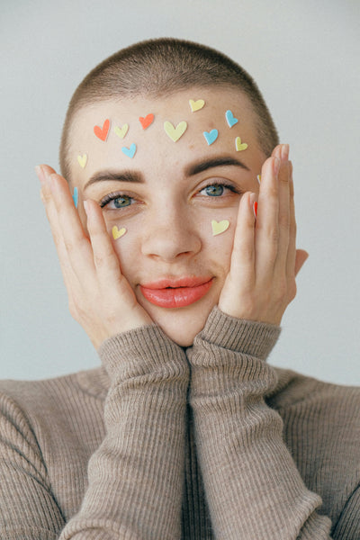 bald woman with heart stickers on face celebrating valentines day