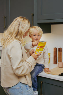 Woman and child in a kitchen looking at a package together