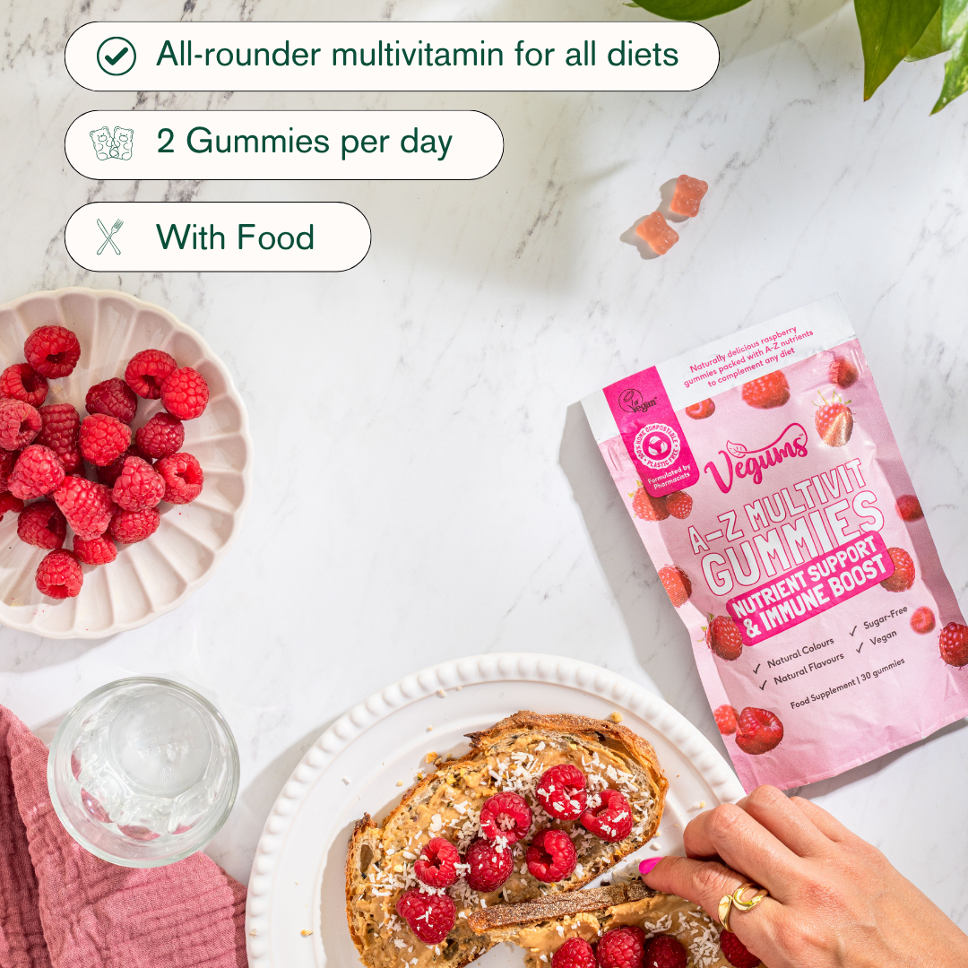 Vitamins gummies packaging with a plate of toast and raspberries on a light surface.