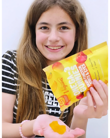 Person holding a package of fruit supplements with a yellow background