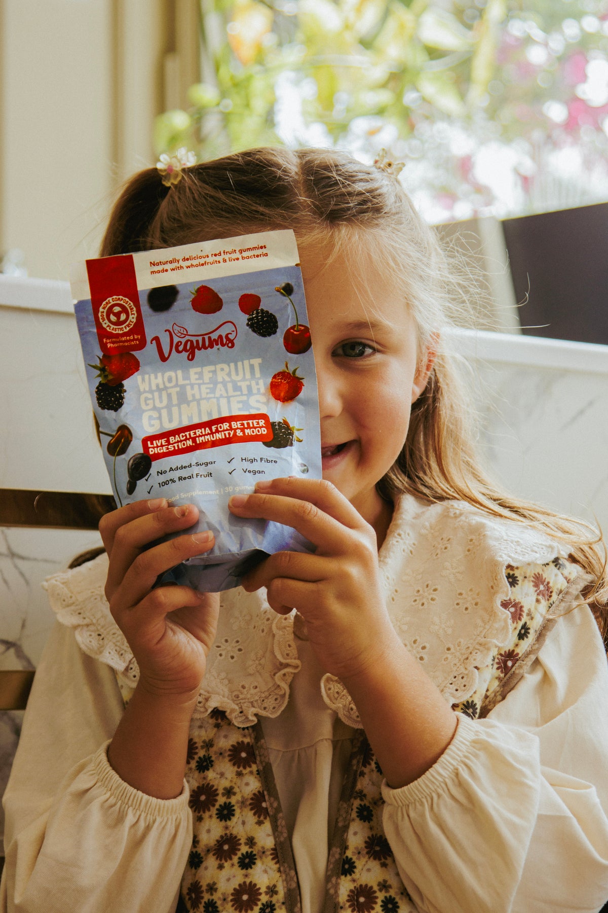 Child holding a package of 'Vegums' whole fruit nut healthy bites', blurred background