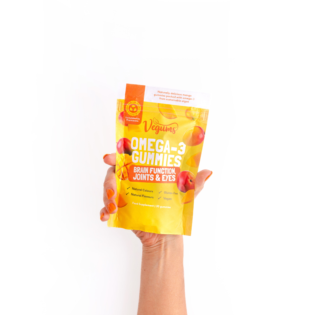 Hand holding a package of Vegans Omega-3 Gummies on a white background