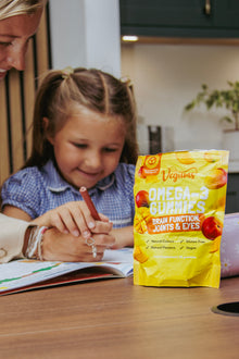 Child with a bag of Vegums Omega-3 Gummies on a table