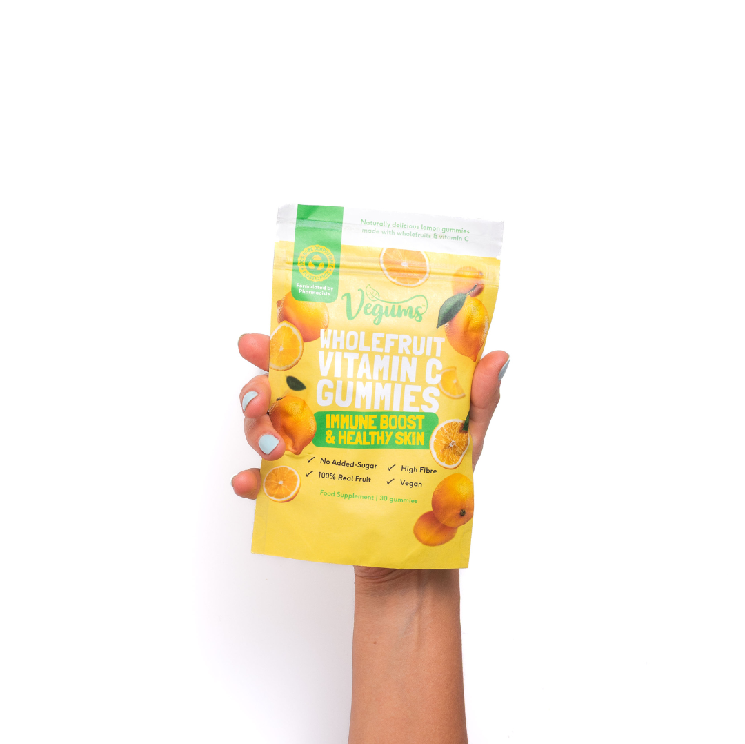 Hand holding a package of Whole Fruit Vitamin C Gummies with a white background