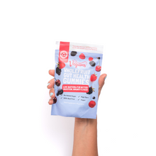 Hand holding a package of 'The Vegums' whole fruit gut health gummies on a white background