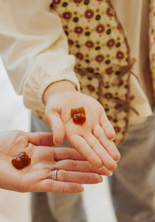 Two hands holding small round jelly-like objects with a blurred background