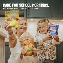 Mum and two children holding Vegums gummy vitamin pouches in a kitchen